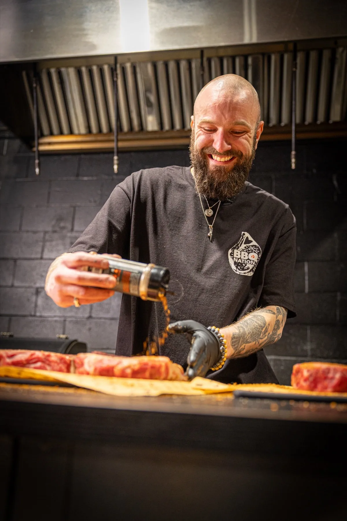 Le formateur du Cours BBQ 101 verse le rub sur une pièce de bœuf