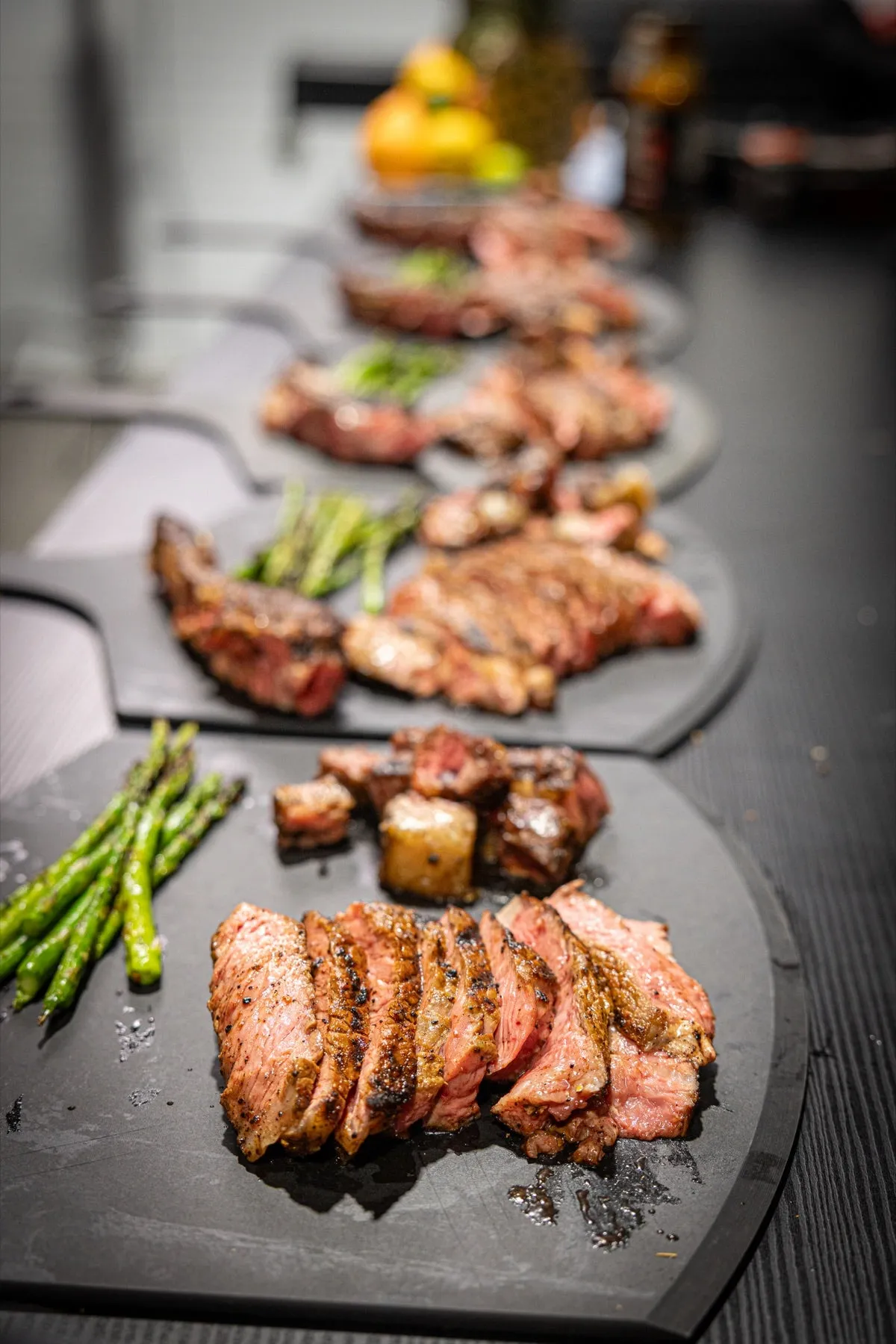 Planches de service alignées le long de la table avec viandes tranchées et asperges grillées
