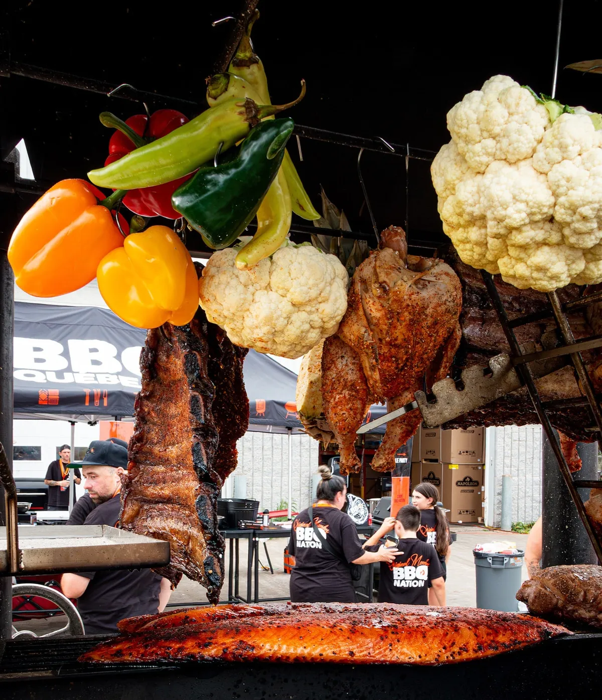 Légumes et viandes suspendus au-dessus du feu à l'asado du Party BBQ Nation 2026