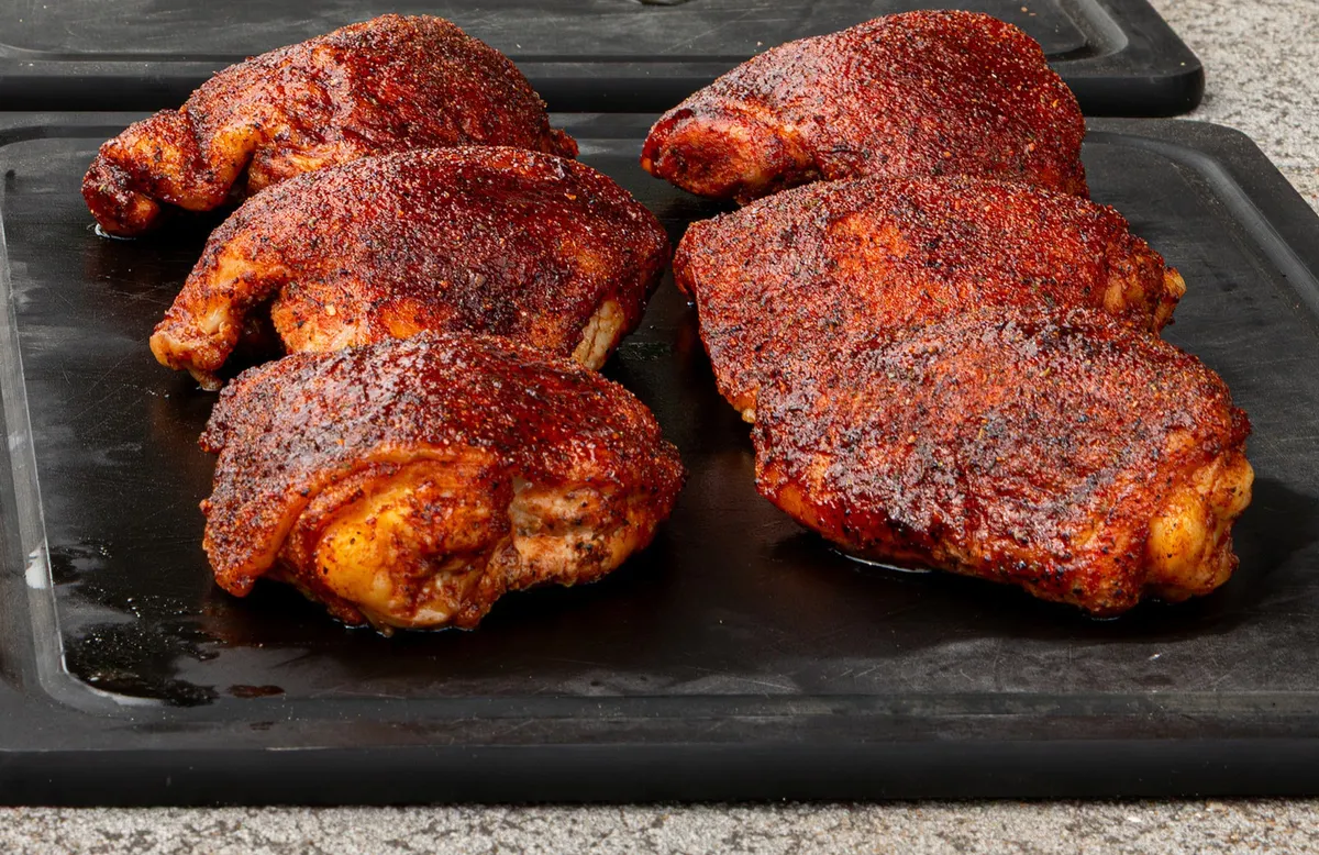 Cuisses de poulet enrobées de rub sur une plaque de cuisson