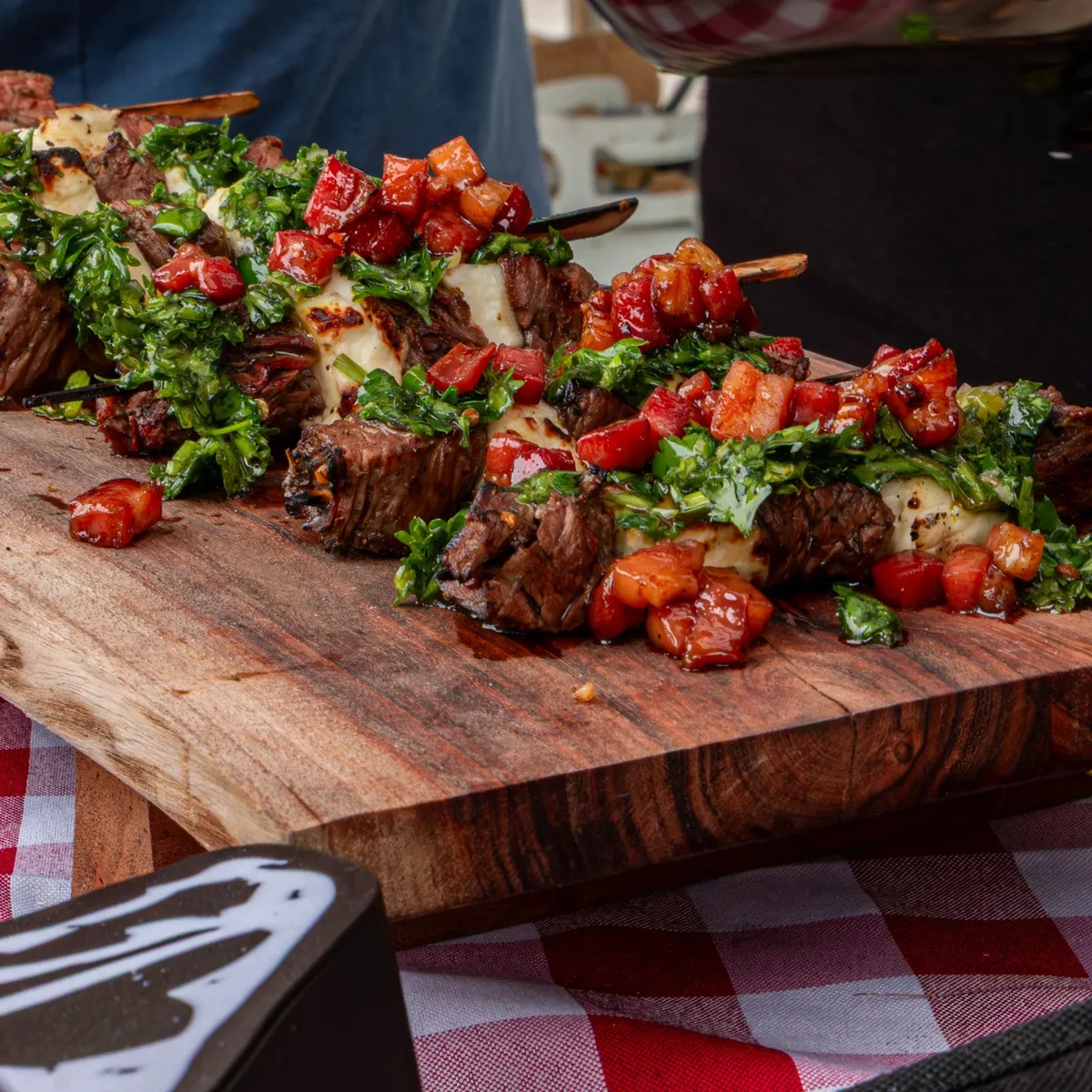 Brochettes de bœuf garnies de chimichurri et de tomates sur une planche de bois